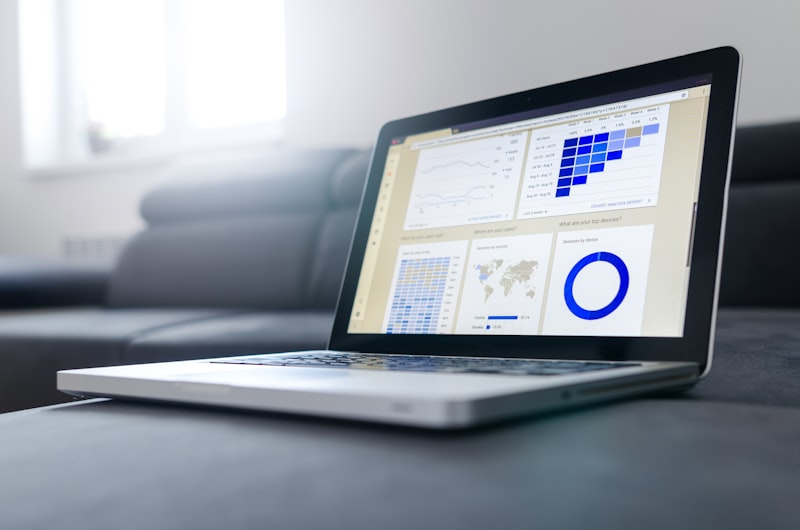 Notebook no sofá exibindo painel de analytics com mapa mundial e gráficos