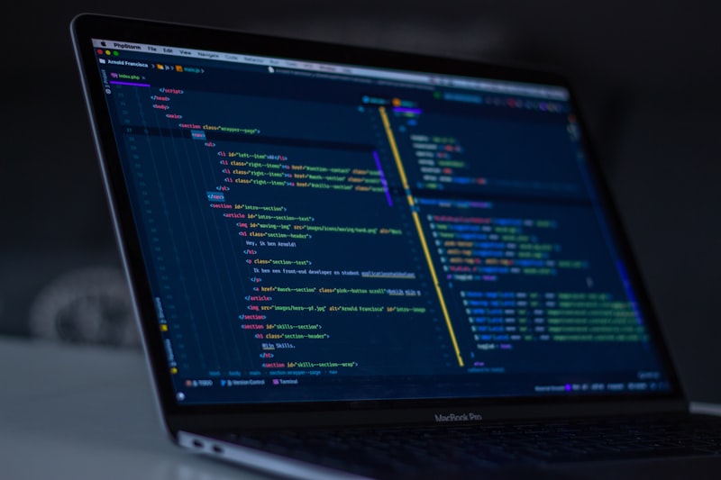 Notebook MacBook com código HTML no editor em tela, em ambiente escuro